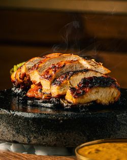 Sliced, grilled tomahawk steak served on a hot stone plate, showcasing charred and juicy organic ingredients. 